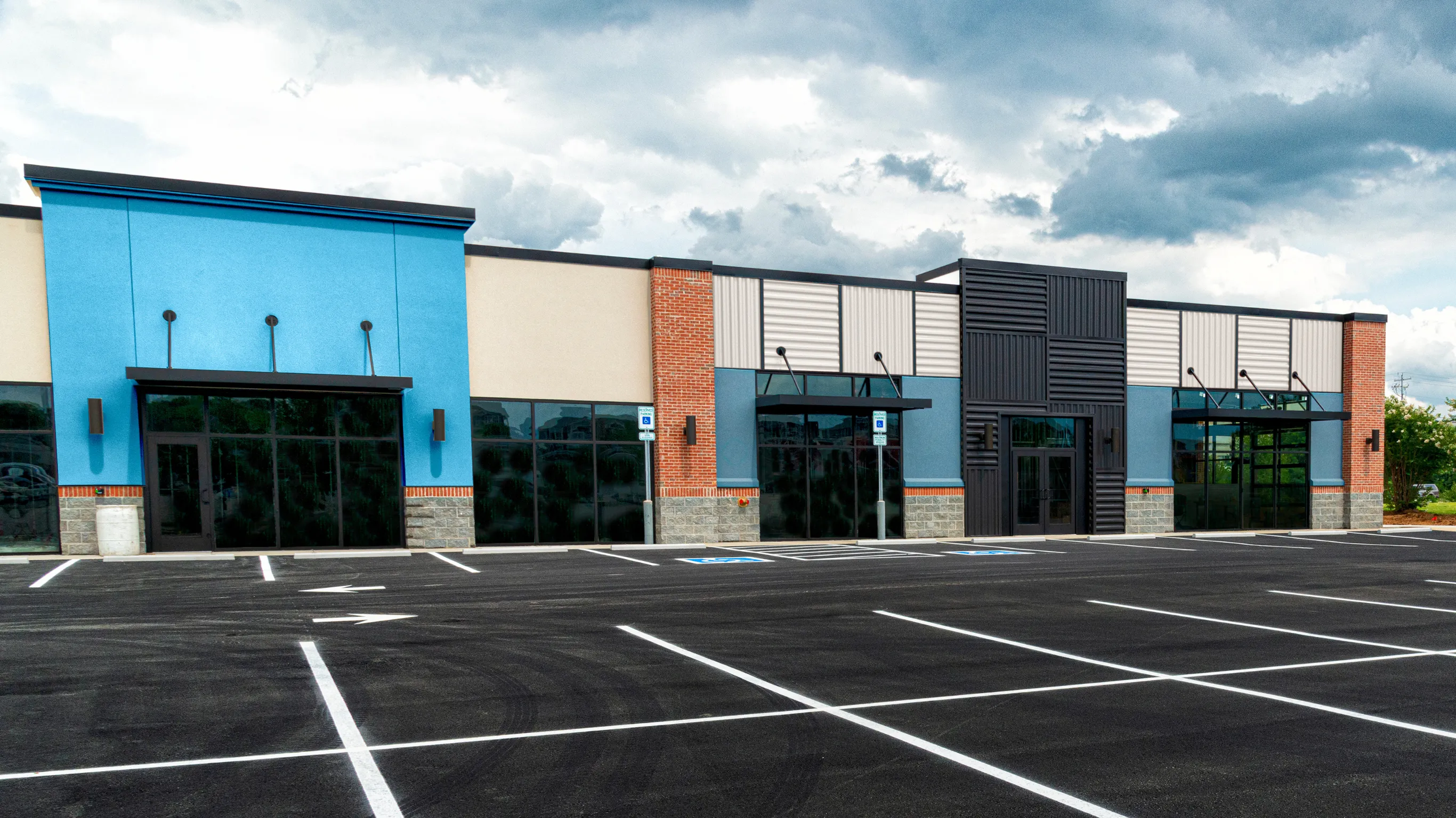 After photo of commercial remodeling project in Los Angeles with updated retail building exterior, modern storefront entrances, blue accent facade, parking lot, and business property improvement