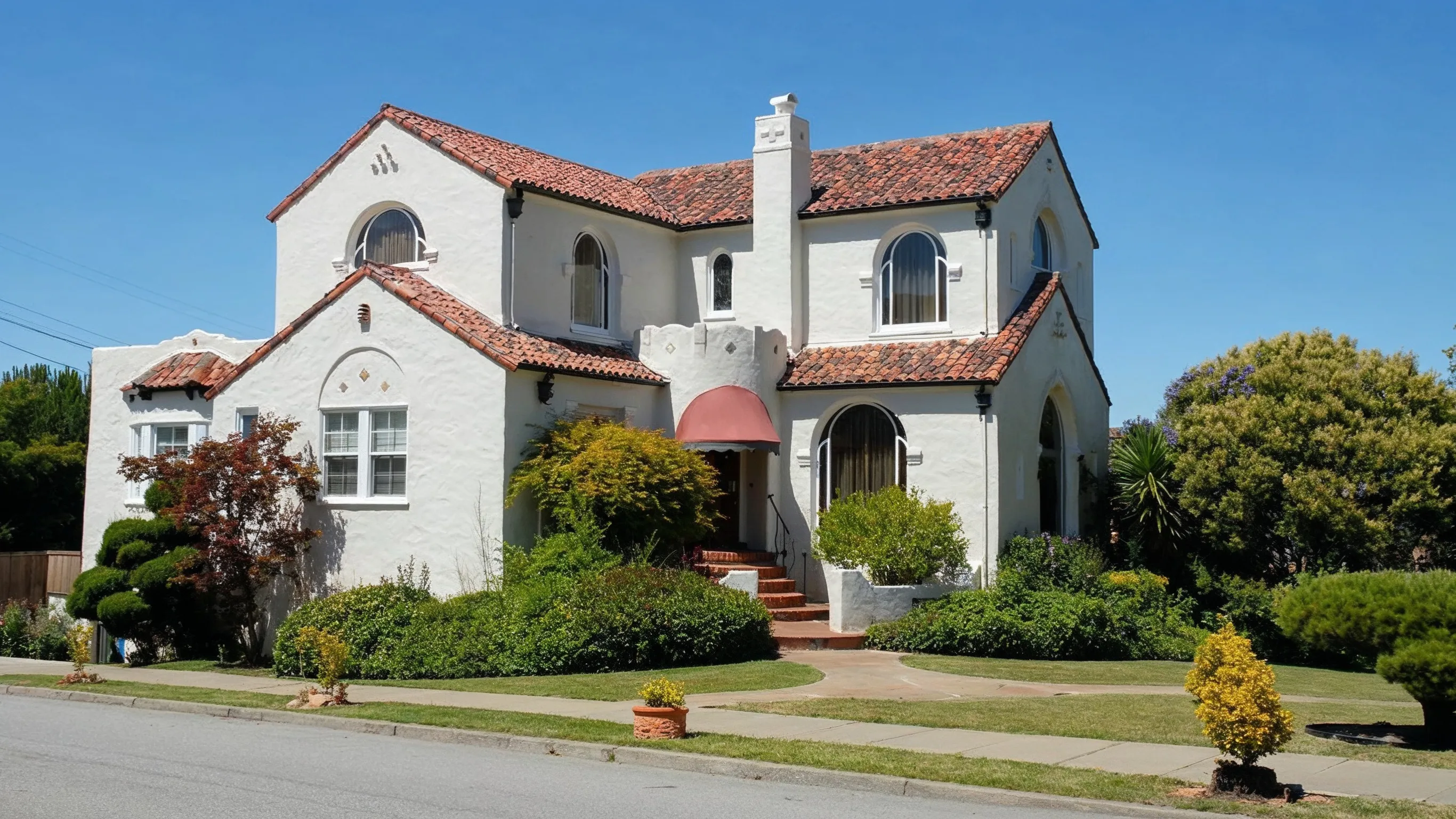 After photo of room addition project in Los Angeles with Spanish-style home exterior, stucco walls, red tile roof, arched windows, landscaping, and expanded residential living space
