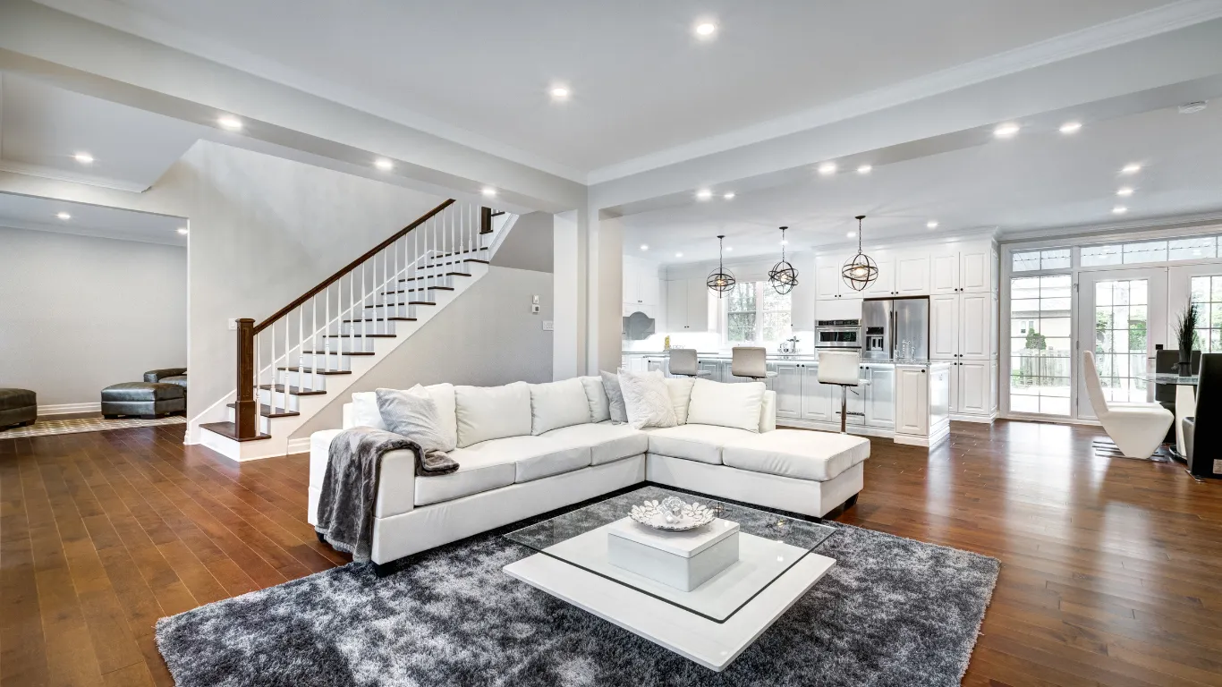 Luxury home remodeling project in Los Angeles with open-concept living room, white kitchen, hardwood flooring, staircase view, recessed lighting, and premium interior finishes