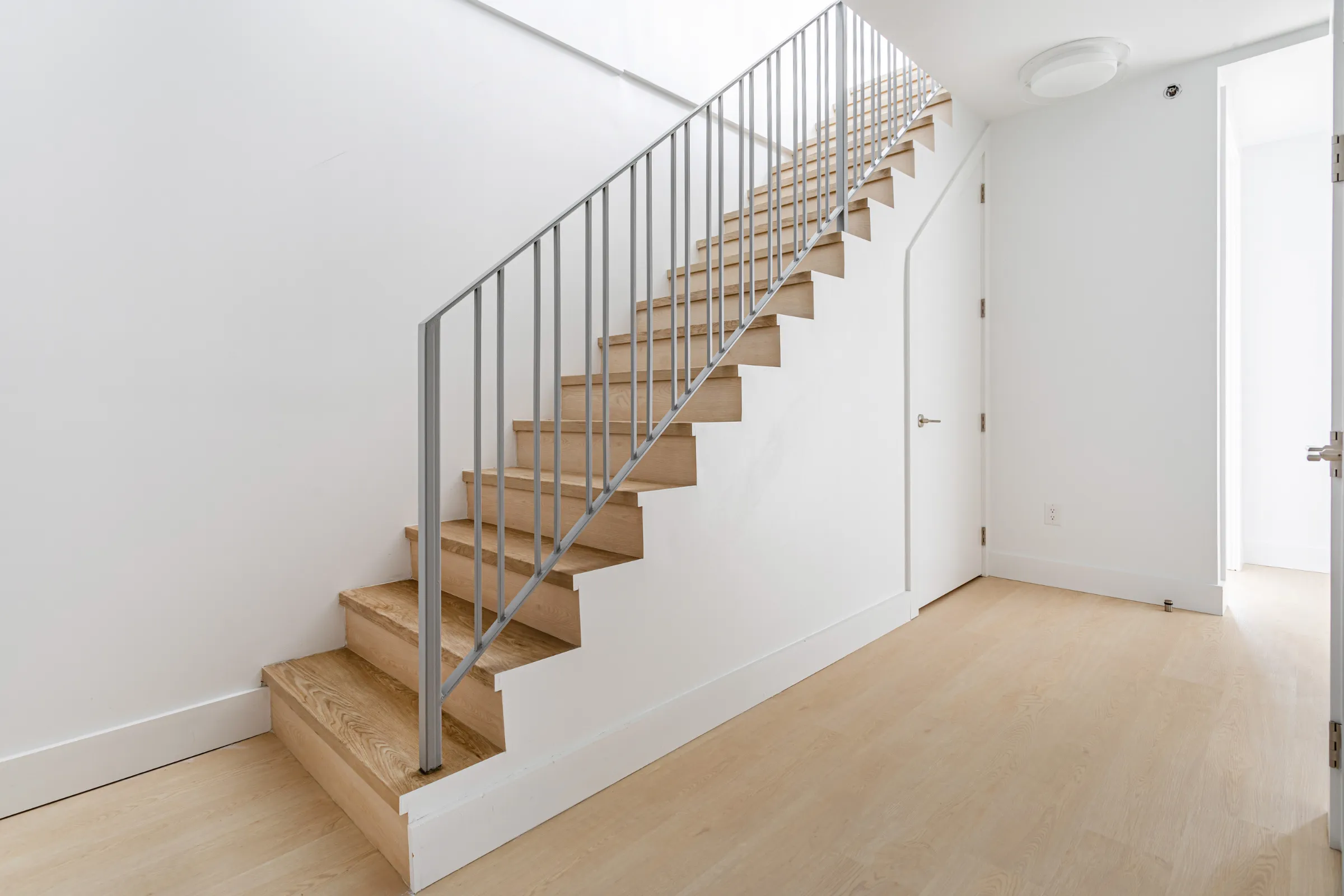 Condo remodeling in Los Angeles with updated kitchen renovation, black cabinets, island layout, white tile flooring, recessed lighting, and open living space