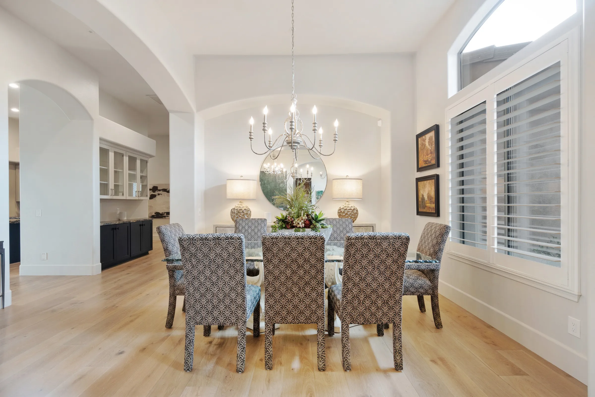 Luxury home remodeling in Los Angeles with elegant dining room, chandelier lighting, arched interior details, wide plank flooring, and premium window shutters